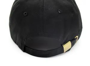 Macro view of adjustable copper buckle and cotton twill texture on black baseball cap