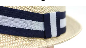 Close-up of natural straw weave texture and navy striped ribbon on a stylish fedora hat