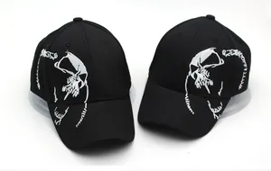 Detailed view of two black cotton baseball caps with white skull embroidery on white background