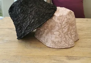 Close-up of pleated bubble fabric texture on black and champagne bucket hats