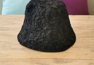Detail shot of black bucket hat showing the unique pleated texture and fabric material