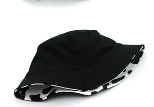 Dettaglio di cappello a secchiello reversibile con tessuto nero, stampa mucca e cuciture rinforzate