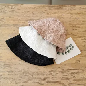 Women pleated bucket hats in black white and pink on wood surface for sun protection
