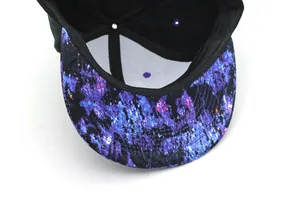 Detail view of the purple nebula galaxy print on the underside of a black snapback cap brim
