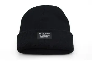 Detailed texture of black knit beanie featuring a white lettered slogan patch on the cuff