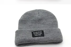Detailed knit texture of a thick grey beanie with a stitched letter patch display