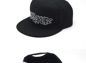 Detailed close-up of white letter embroidery on a black flat brim snapback baseball cap