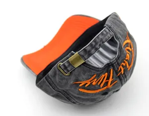 Detail of washed grey baseball cap featuring orange embroidery and metal buckle strap