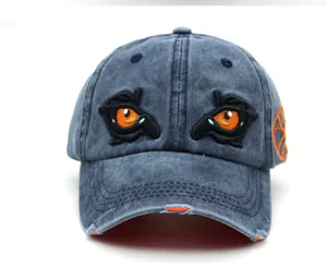 Detail of embroidered eagle eyes on distressed blue denim baseball cap with orange lining