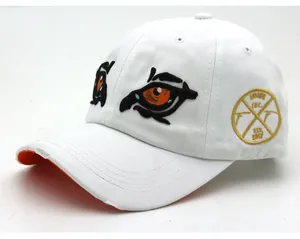 Detail of cartoon eagle eye embroidery and distressed brim on white cotton baseball cap
