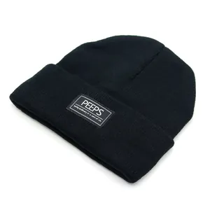 Detail van de PEEPS-logopatch en ribtextuur op een zwarte gebreide wintermuts