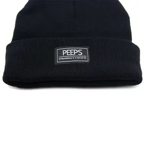 Detailweergave van de geribbelde breistructuur en PEEPS-patch op de zwarte winter muts