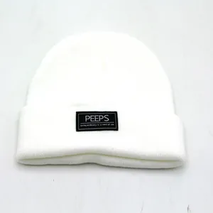Detailweergave van de PEEPS-patch op de witte gebreide muts met fijne textuur