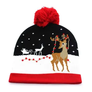 Knitted Christmas beanie with red pompom featuring reindeer jacquard winter patterns
