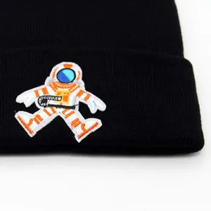 Black knitted beanie hat featuring a detailed astronaut embroidery patch for winter