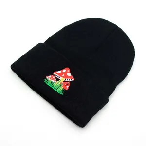 Detailed close-up of mushroom embroidery on a black ribbed knit beanie cuff for winter