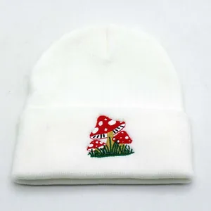White knitted beanie with mushroom embroidery featuring a classic cuffed design for winter