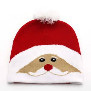 Close-up of a red knitted Christmas beanie with Santa Claus face and a white pom-pom