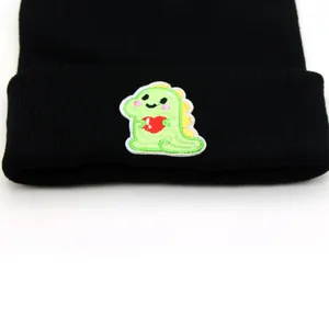 Black ribbed knit beanie featuring a cute green cartoon dinosaur embroidery patch