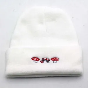 Détail de broderie de champignons rouges sur un bonnet en tricot blanc d'hiver