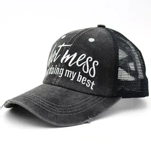 Detail of embroidered hot mess text and distressed brim on washed grey mesh baseball cap