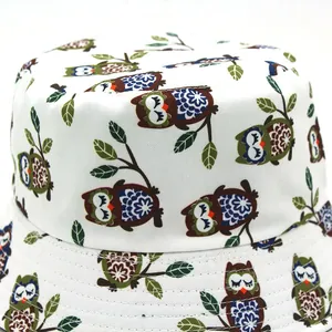 Reversible bucket hat with cute cartoon owl print and green leaf patterns in white