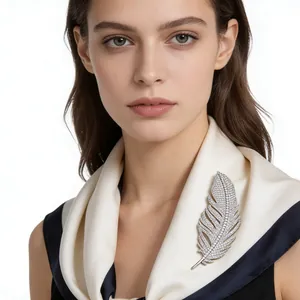 Detailed close-up of feather brooch with micro-pave crystals on a white silk scarf