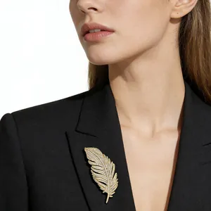 Close-up of elegant gold feather brooch with crystals on a black suit jacket