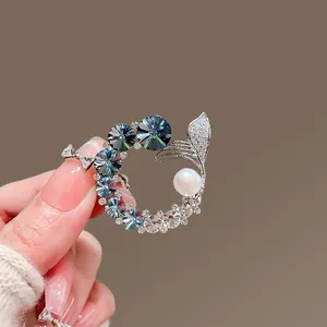 Detail of crystal fish tail brooch with blue rhinestones and a white pearl accent