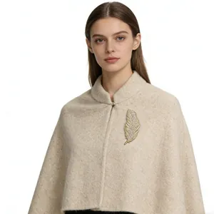 Detailed view of a golden feather brooch with crystals on a beige coat lapel