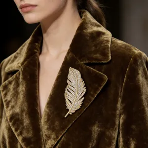 Exquisite gold feather brooch with sparkling crystals pinned on a brown velvet lapel