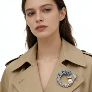 Elegant rhinestone ocean fishtail brooch with blue gemstones and white pearl on a coat