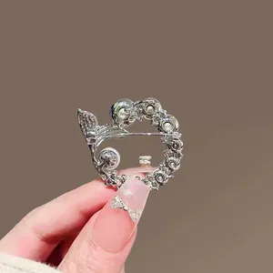 Close-up of silver hollow wreath brooch with pearls and rhinestones on a hand