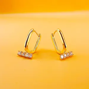 Gold rectangular U-shaped hoop earrings with micro-set cubic zirconia on orange background