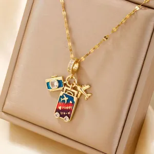 Detailed macro view of golden necklace with camera, aircraft, and travel suitcase pendants