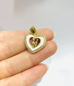 Detailed view of a gold heart pendant with zircon stones and mother-of-pearl inlay