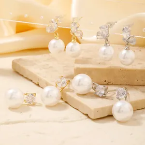 Elegant gold and silver butterfly earrings with white pearls on a stone tray