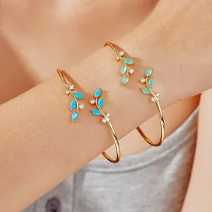 Golden willow branch bangles set with turquoise leaves and zircon accents on wrist