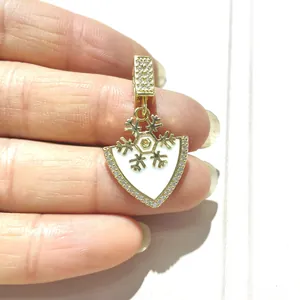 Detailed view of gold shield pendant with white enamel snowflake and zircon accents