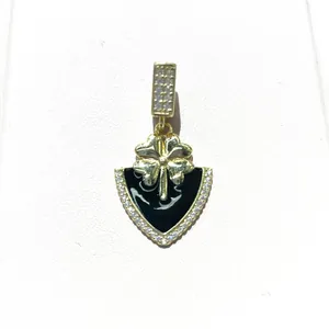 Macro shot of gold-plated clover pendant with black enamel shield and zircon inlay