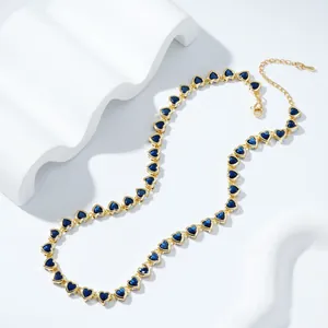 Gold-plated heart necklace featuring vibrant blue zircon stones on a white wavy display