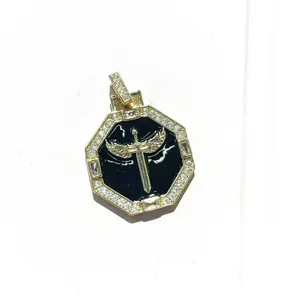 Macro detail of octagonal gold pendant with black enamel angel sword and cubic zirconia