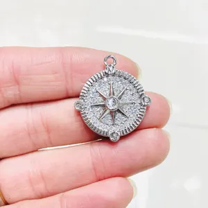 Dettaglio del ciondolo a bussola in argento con zirconi incastonati e lettere direzionali