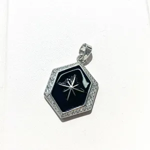 Macro detail of hexagonal pendant with black enamel, star pattern, and zircon border