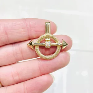 Ciondolo dorato con zirconi micro-pavé tenuto in mano per mostrare la scala reale