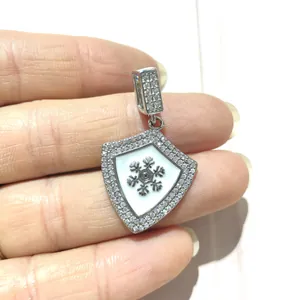 Detailed macro shot of silver shield pendant with inlaid zircon and metal snowflake