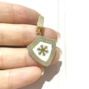 Macro view of shield-shaped gold pendant with micro-paved zircons and snowflake motif