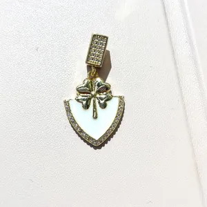 Detailed macro view of gold clover shield pendant with white enamel and pavé zircons