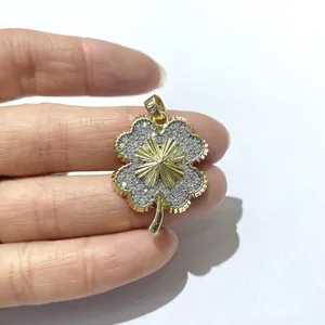 Dettaglio del ciondolo a quadrifoglio dorato con zirconi incastonati e motivo radiale