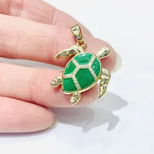 Goldener Schildkrötenanhänger mit grüner Emaille und Zirkonia-Inlay in der Hand